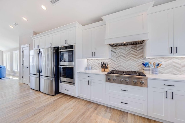 kitchen with white cabinets, custom range hood, appliances with stainless steel finishes, and light countertops