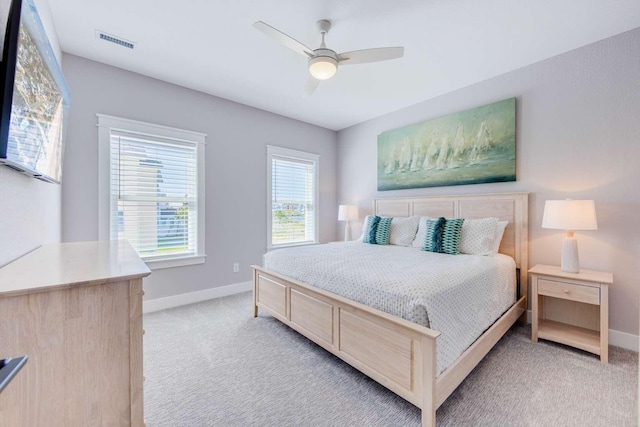 bedroom with light colored carpet, ceiling fan, visible vents, and baseboards