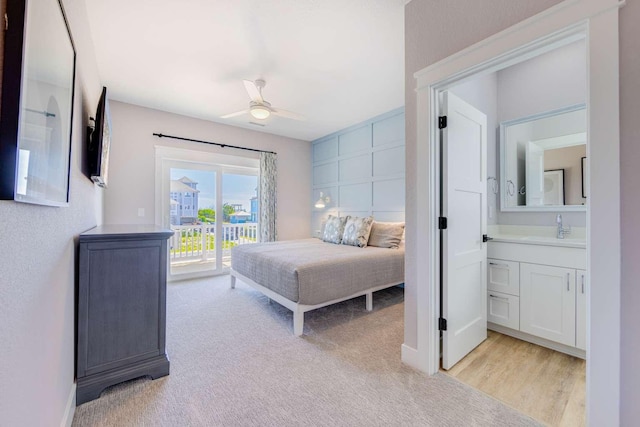 bedroom featuring light carpet, access to outside, a sink, and a ceiling fan