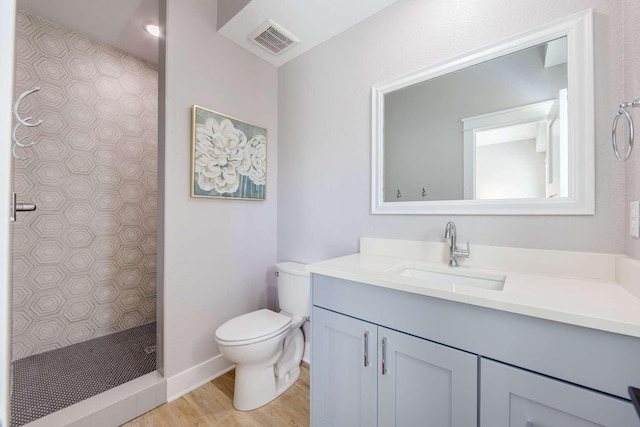 full bath featuring visible vents, toilet, wood finished floors, vanity, and a walk in shower