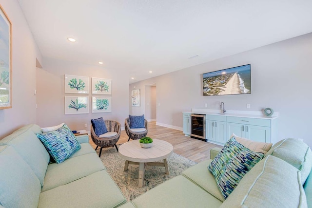 living room featuring wine cooler, recessed lighting, baseboards, light wood-style floors, and indoor wet bar