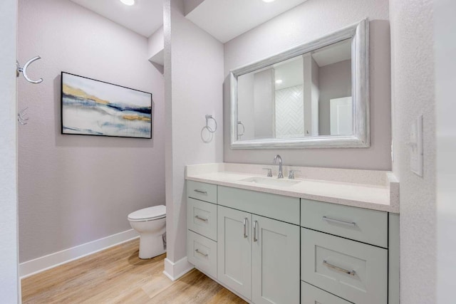 bathroom featuring toilet, vanity, baseboards, and wood finished floors