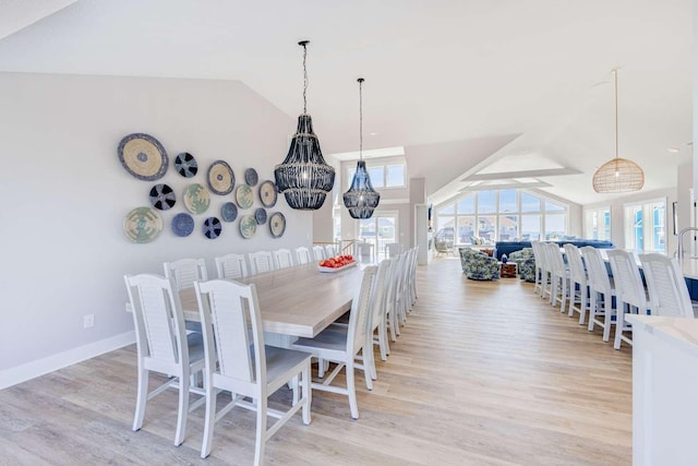 dining space featuring lofted ceiling, light wood finished floors, and baseboards