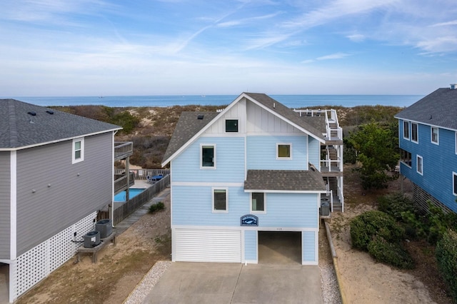 exterior space with central AC, a water view, driveway, roof with shingles, and board and batten siding