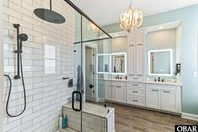 bathroom with double vanity, an inviting chandelier, a stall shower, and a sink