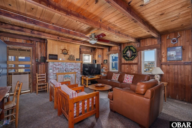 living room featuring wood walls, wood ceiling, a brick fireplace, beam ceiling, and carpet