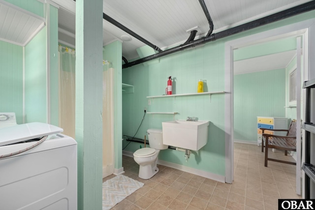 full bath with washer / dryer, curtained shower, a sink, and toilet