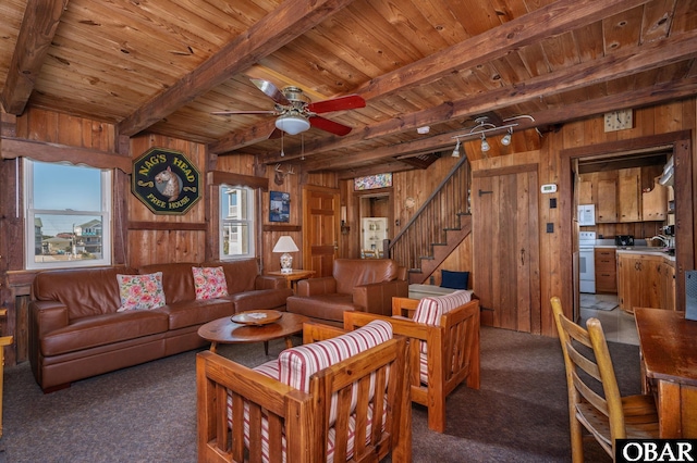 living room featuring wooden walls, wood ceiling, beamed ceiling, carpet, and stairs