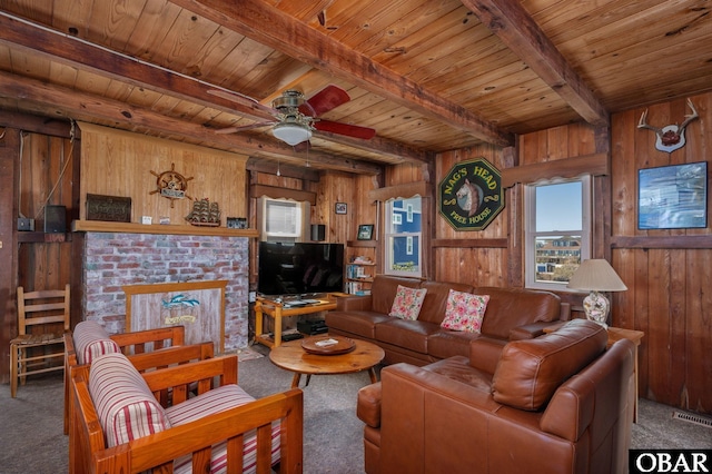 carpeted living room featuring wooden ceiling, wooden walls, a fireplace, visible vents, and beamed ceiling