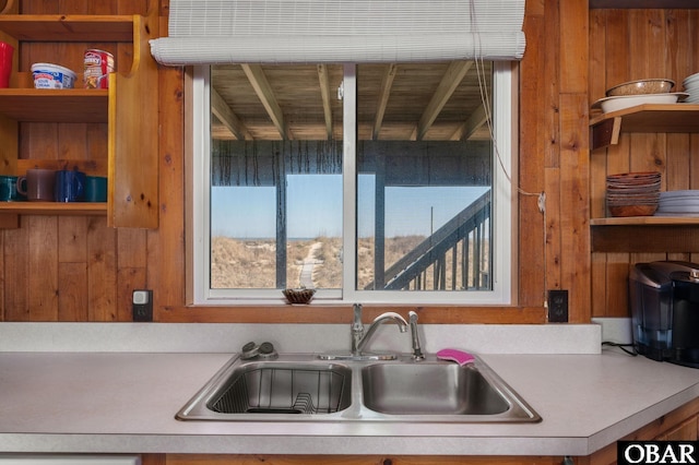 kitchen featuring light countertops, open shelves, and a sink