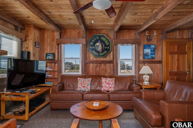 carpeted living room with wood walls, wood ceiling, a ceiling fan, and beamed ceiling