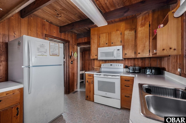 kitchen with white appliances, wooden walls, brown cabinetry, beamed ceiling, and a sink