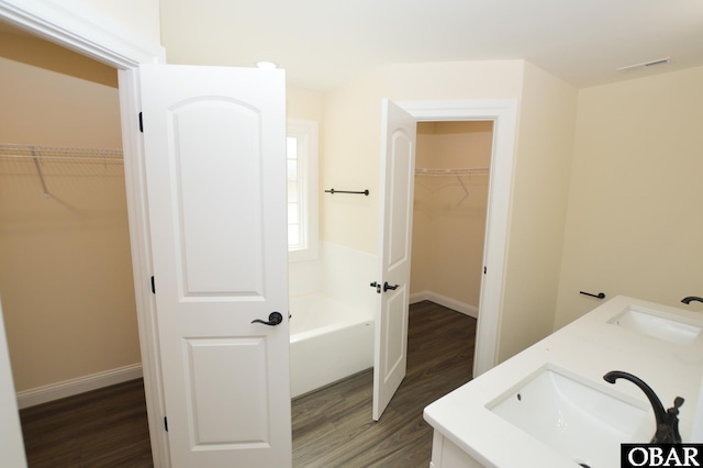 bathroom featuring a tub to relax in, visible vents, a sink, and wood finished floors