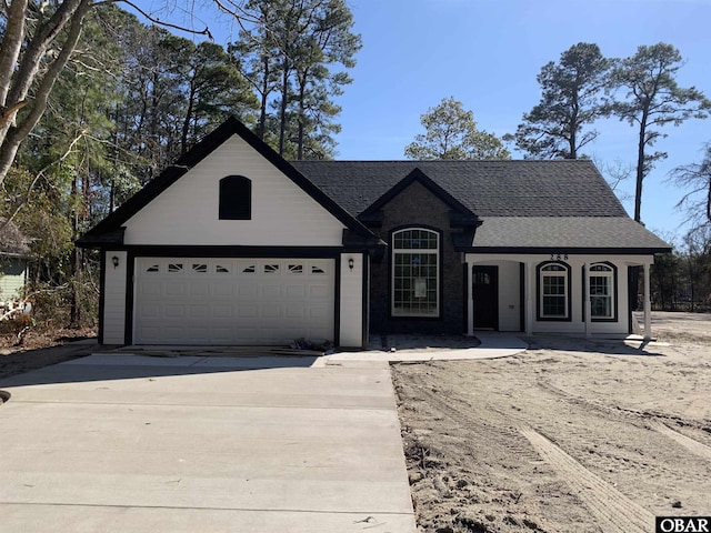 view of front of property featuring a garage, concrete driveway, and roof with shingles