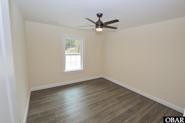 unfurnished room with ceiling fan, dark wood finished floors, and baseboards