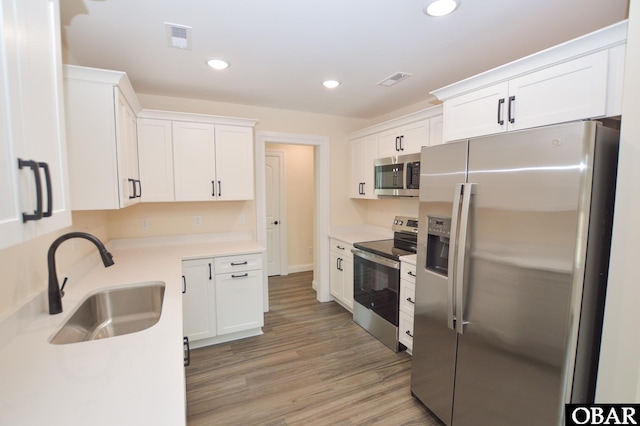 kitchen with visible vents, appliances with stainless steel finishes, white cabinetry, a sink, and recessed lighting