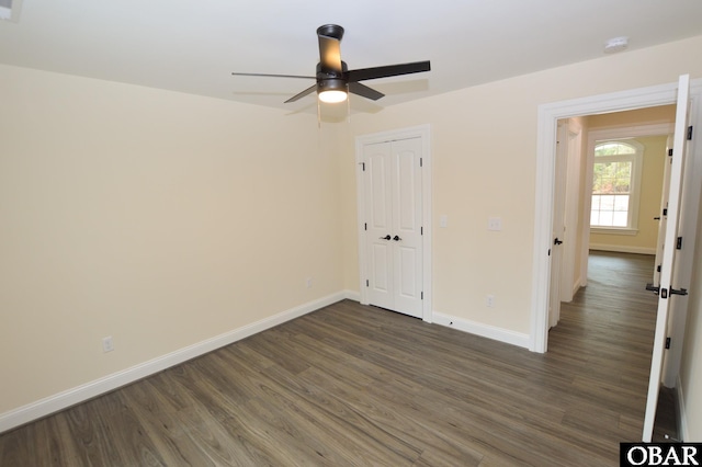 spare room with dark wood finished floors, baseboards, and ceiling fan