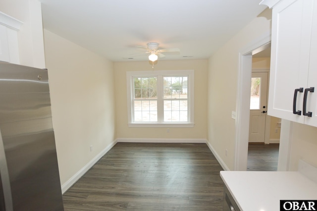 unfurnished room featuring dark wood-style floors, a healthy amount of sunlight, ceiling fan, and baseboards