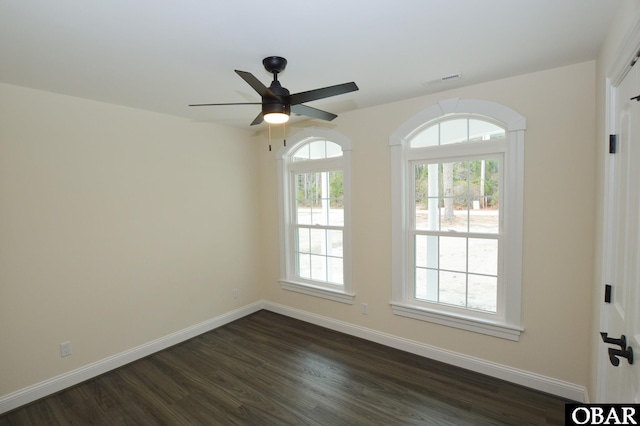 unfurnished room featuring dark wood-type flooring, visible vents, ceiling fan, and baseboards