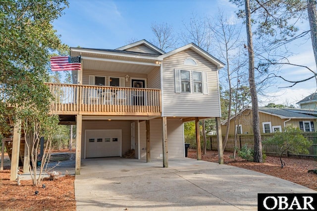 view of front of property featuring a porch, a garage, fence, concrete driveway, and a carport