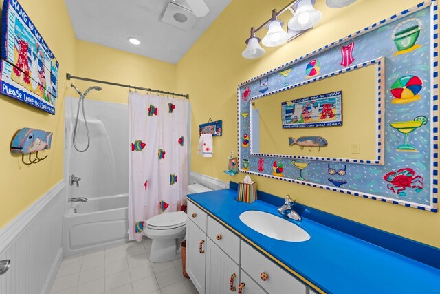 bathroom featuring shower / tub combo with curtain, toilet, wainscoting, vanity, and tile patterned floors