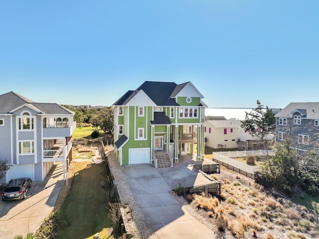 beach home featuring an attached garage, stairs, a residential view, and concrete driveway