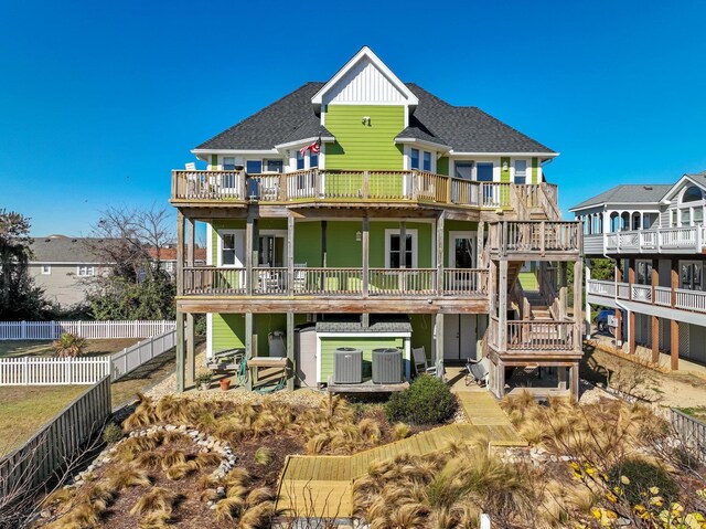 back of house with central AC, roof with shingles, a wooden deck, and fence