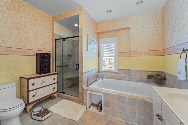 bathroom with wallpapered walls, toilet, a garden tub, vanity, and a shower stall