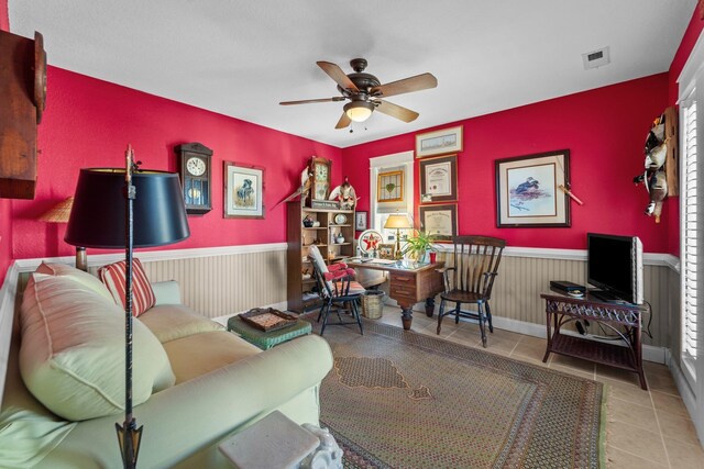 living area featuring a ceiling fan, wainscoting, visible vents, and tile patterned floors