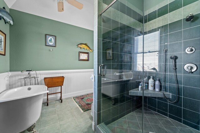 bathroom with ceiling fan, a freestanding tub, wainscoting, a shower stall, and tile patterned floors