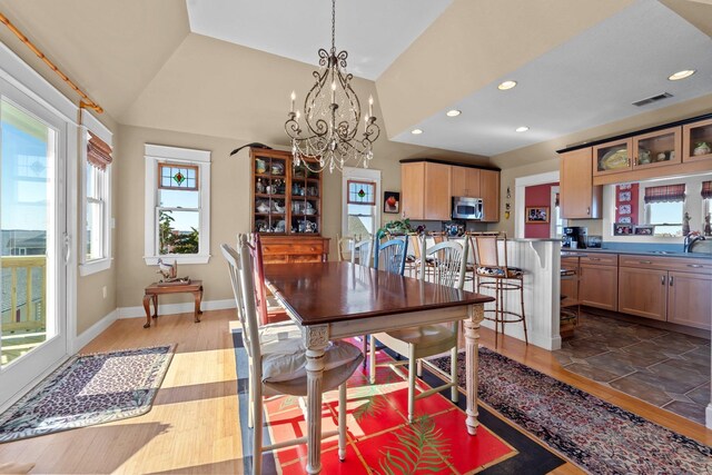 dining area with lofted ceiling, recessed lighting, wood finished floors, visible vents, and an inviting chandelier