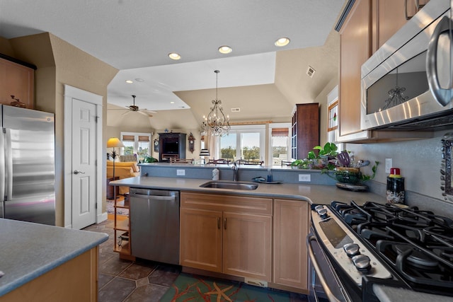 kitchen featuring a peninsula, a sink, hanging light fixtures, appliances with stainless steel finishes, and light countertops