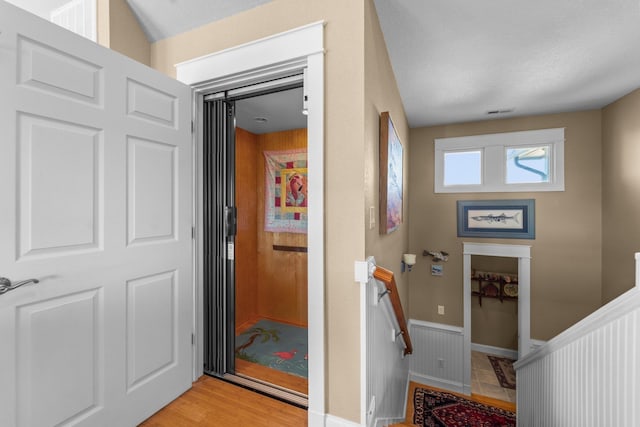 interior space featuring a wainscoted wall, visible vents, and light wood-style flooring