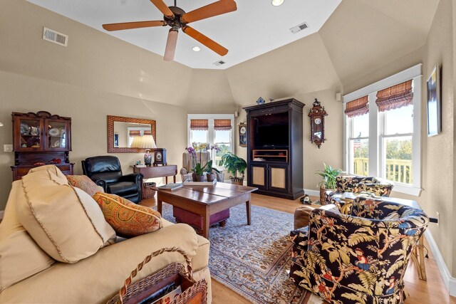 living area with lofted ceiling, light wood finished floors, visible vents, and baseboards