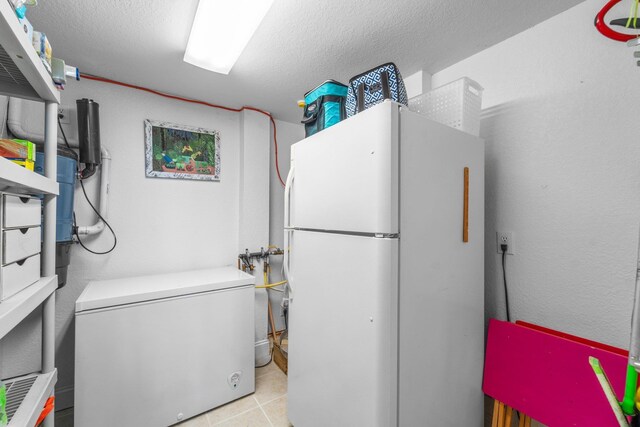 washroom with a textured ceiling and light tile patterned floors