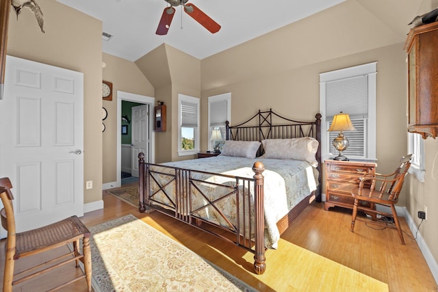 bedroom featuring baseboards, visible vents, vaulted ceiling, and wood finished floors