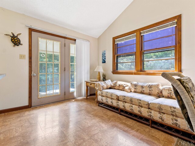 living area with light floors, baseboards, and vaulted ceiling