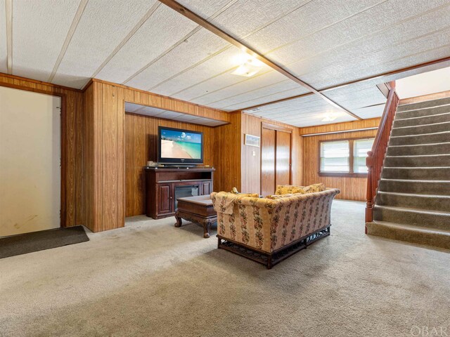 living area featuring wooden walls, carpet, and stairway