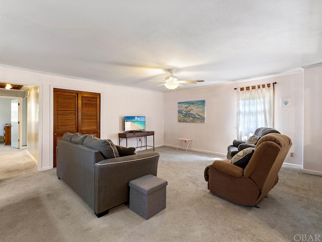 living area with ornamental molding, light colored carpet, ceiling fan, and baseboards