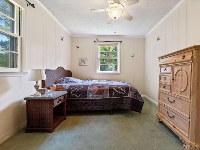 carpeted bedroom featuring a textured ceiling, a ceiling fan, and crown molding