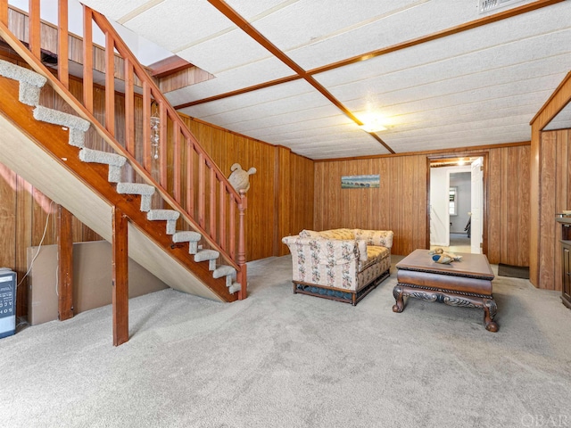 carpeted living room with stairs and wooden walls