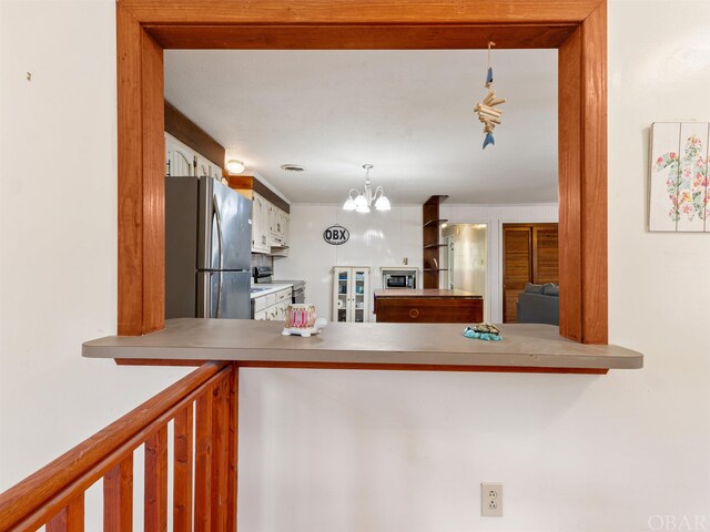 kitchen with a chandelier, appliances with stainless steel finishes, decorative light fixtures, light countertops, and white cabinetry