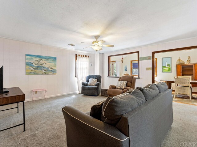 carpeted living area with ceiling fan, a textured ceiling, and baseboards