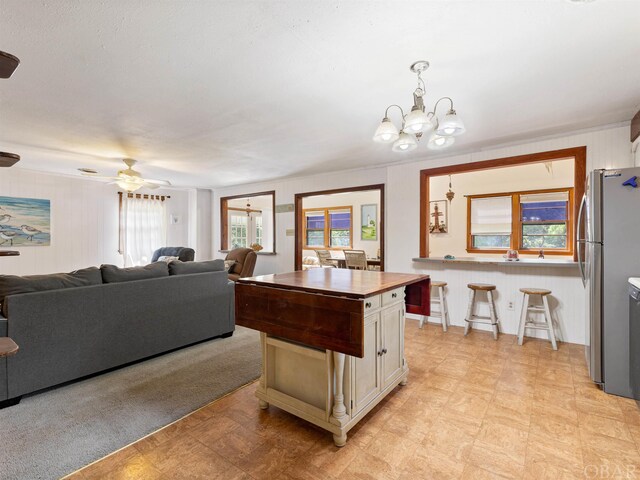 kitchen featuring white cabinets, a breakfast bar area, open floor plan, decorative light fixtures, and freestanding refrigerator