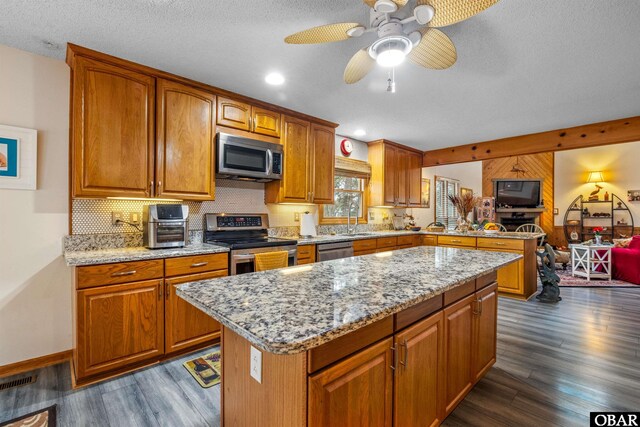 119 Baycliff Trl Lot 119, Kill Devil Hills, NC 27948 - kitchen with appliances with stainless steel finishes, dark wood-type flooring, a peninsula, brown cabinetry, and a textured ceiling