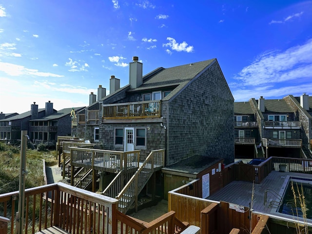 rear view of house with a balcony, roof with shingles, and a chimney