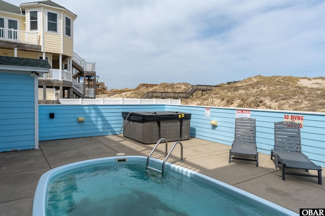 view of pool with stairway and a hot tub