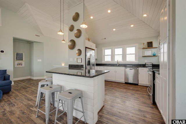 kitchen featuring dark wood-style floors, a breakfast bar area, lofted ceiling, stainless steel appliances, and wooden ceiling