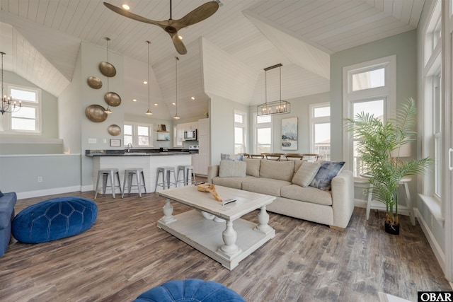 living room with a healthy amount of sunlight, wood finished floors, baseboards, and high vaulted ceiling