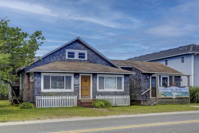 view of front facade with roof with shingles and a fenced front yard